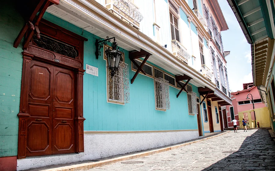 Fachada turquesa de Casa Cino Fabiani con su portón de madera, sobre la calle empedrada de Las Peñas